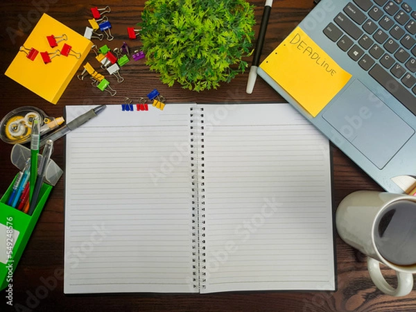 Fototapeta Flat lay, a mockup of a notebook. A workspace with white notebooks, laptops, office supplies,and coffee cups in the office background of a wooden desk from top view.