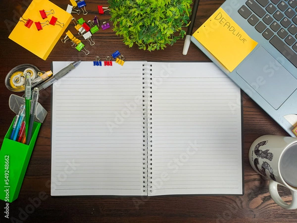 Fototapeta Flat lay, a mockup of a notebook. A workspace with white notebooks, laptops, office supplies, pencils, and coffee cups in the office background of a wooden desk from top view.