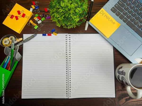Fototapeta Flat lay, a mockup of a notebook. A workspace with white notebooks, laptops, office supplies, pencils, and coffee cups in the office background of a wooden desk from top view.