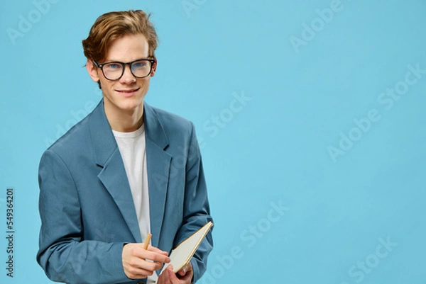Fototapeta a funny guy in a strict suit for office work is wearing glasses and holding an empty notepad in his hands