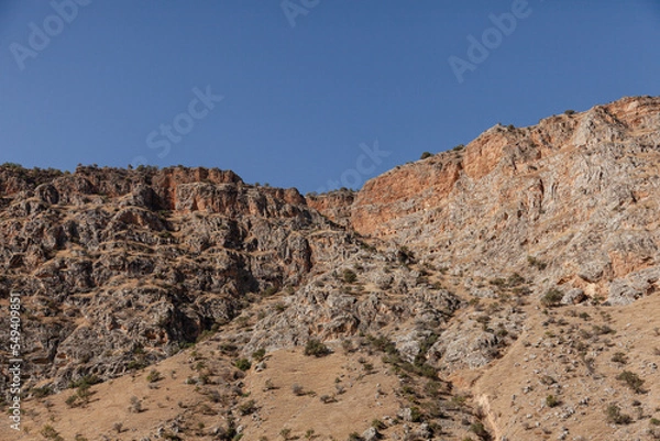 Fototapeta View of a steep rocky valley with blue sky.