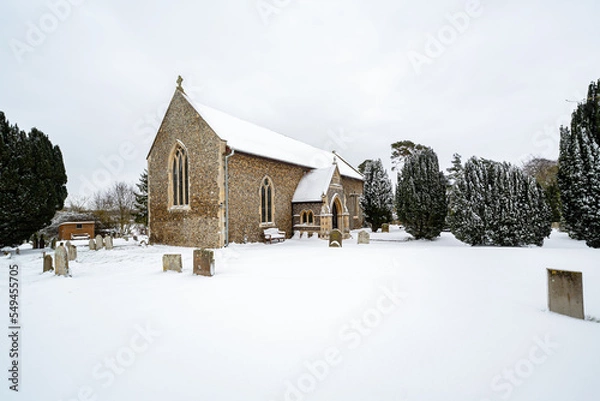 Fototapeta All Saints church in the small village of Sutton in the British countryside, it is totally covered in deep snow during a rare snow storm in the UK