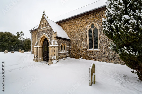 Fototapeta All Saints church in the small village of Sutton in the British countryside, it is totally covered in deep snow during a rare snow storm in the UK