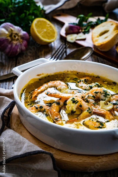 Fototapeta Roast prawns in butter sauce with lemon, garlic and parsley on wooden table
