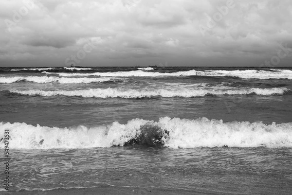 Obraz Panoramic view from the beach on the waves of the North Sea with a number of fishing boats in the distance.