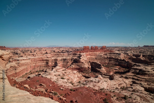 Fototapeta View from the Maze Overlook in the Maze District of Canyonlands National Park in, Utah. A few clouds are seen on the horizon in an otherwise clear sky. A labyrinth of canyons is visible.