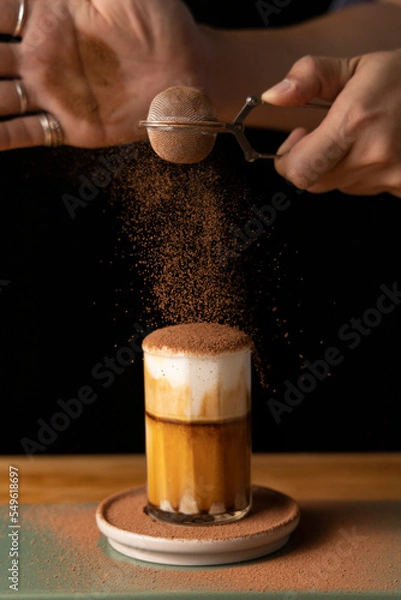 Obraz Selective focus Close up made mocha latte or chocolate coffee , Hand sprinkled chocolate powder on glass.