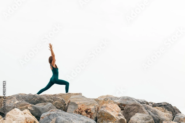 Fototapeta Portrait of fit woman practicing various yoga asanas  outdoors by the sea, doing crescent pose or high lunge, ashta chandrasana in nature. Energy, flexibility, strength and power concept. Copy space