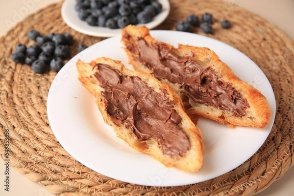 Fototapeta Tasty croissant with chocolate paste and blueberries on beige background