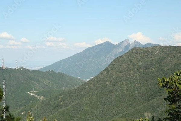 Fototapeta Picturesque view of mountains and trees under cloudy sky