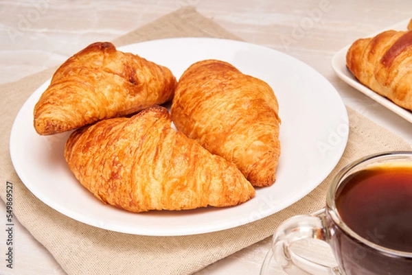 Obraz 3 butter crossaint, accompanied by a cup of coffee on a marble surface. French breakfast concept.