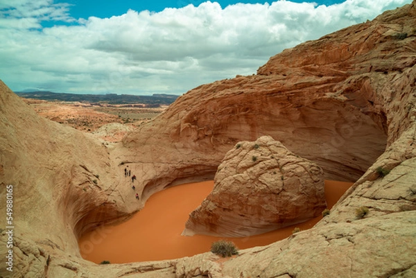 Fototapeta Hikers visit a unique sandstone geological feature known as the 'Cosmic Ashtray' located in Grand Staircase-Escalante National Monument in southern Utah. Several people attempt to descend into the pit