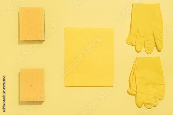 Fototapeta Layout of detergents. Rubber gloves, foam sponge, fabric rag on a yellow background. Cleaning concept