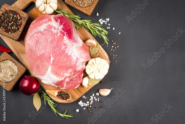 Fototapeta View above raw boneless pork shoulder ready for roasting with seasoning over dark concrete background with copy space. Organic meat for main dish