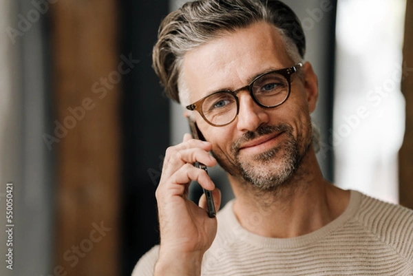 Obraz Closeup of white middle-aged man talking on cellphone while standing indoors
