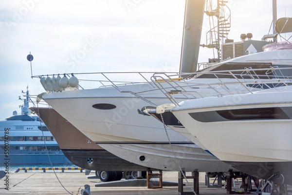 Fototapeta Stern nose of sea yachts and boats installed on special supports for storage and maintenance of ships in the docks.