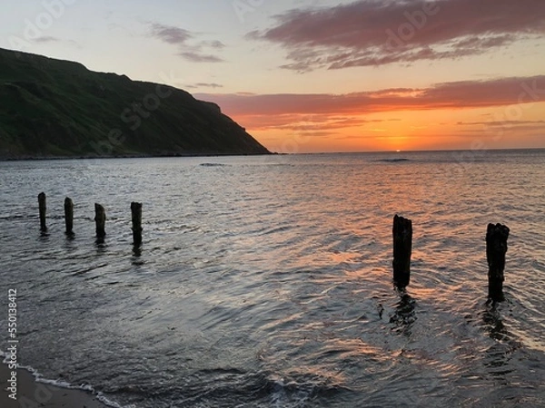 Obraz Old weathered posts on beach at sunset, Gardenstown, Scotland