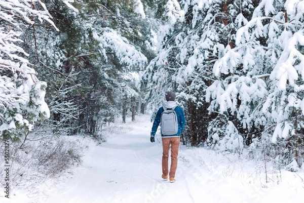 Fototapeta man walking alone in a beautiful snowy forest. Mental health concept