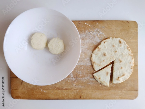 Fototapeta Piadina ready to be tasted on a cutting board with two flour dough. Typical italian dish concept. Top view, flat lay.