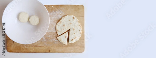 Fototapeta Piadina ready to be tasted on a cutting board with two flour dough. Typical italian dish concept. Top view, flat lay, copy space, banner
