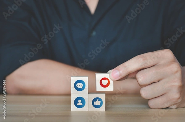 Fototapeta Hand putting wooden cube symbol of Social media and digital online concept. living on vacation and playing social media. Social Distancing ,Working From Home concept
