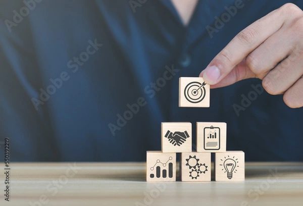 Fototapeta business strategy, Action plan, Goal and target, hand stack woods block step on table with icon about business strategy and Action plan. business development concept. copy space