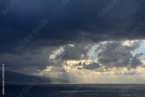 Fototapeta the sun rays shine through the clouds on the sea surface