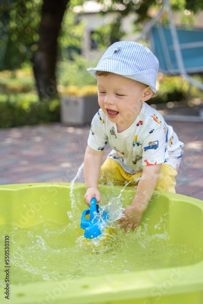 Fototapeta Boy playing with water in the yard in summer