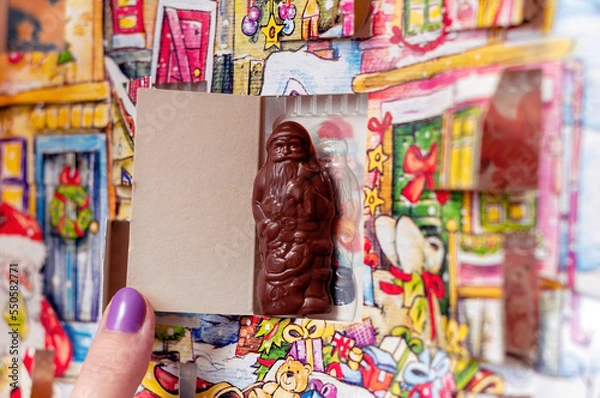 Fototapeta Santa Claus Christmas advent calendar chocolate in a box, girl opening a choco gift