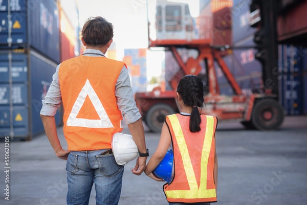 Obraz back side Asian father who owns an import-export industry and warehouse business. Holding hard hat and introducing and educate her knowledge  of work for a daughter who wants to learning