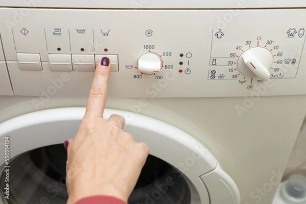 Fototapeta A person chooses a washing mode with a switch.