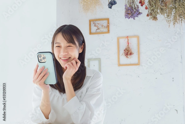 Obraz スマートフォンを見て笑う若い女性