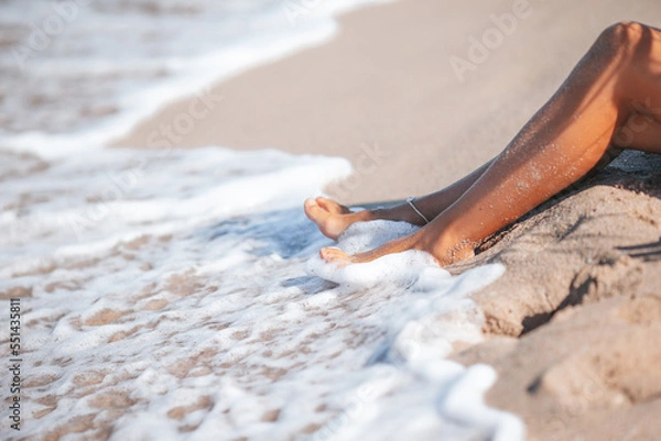 Fototapeta Closeup of woman legs splashing in shallow water on the beach