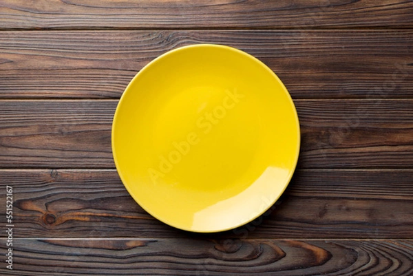 Obraz Top view of empty yellow plate on wooden background. Empty space for your design