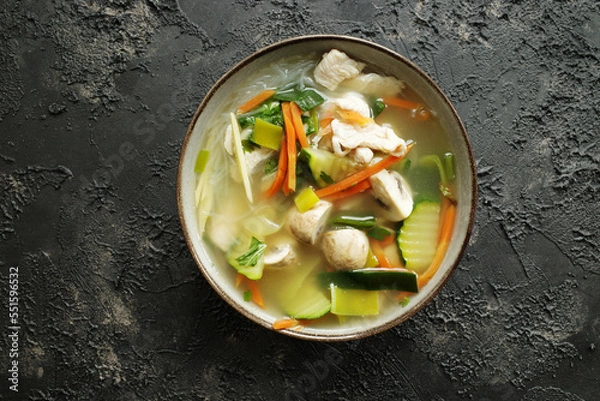 Fototapeta Chicken soup with veggies and glass noodles on a dark textured background