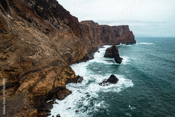 Fototapeta Rocky coastal peninsula Ponta de Sao Lourenco in Madeira island cliffside against dramatic ocean waves under cloudy skies
