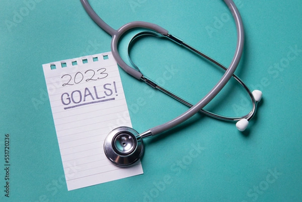 Fototapeta Stethoscope on color background New Year resolution Goals word as medical concept with blank paper and space for text .