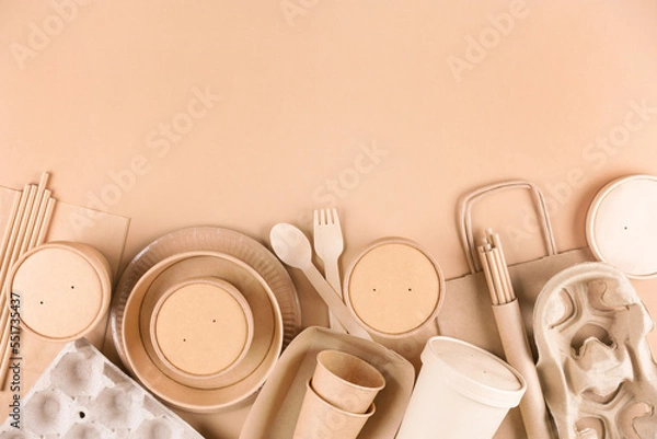 Fototapeta Paper utensils, cups, plates, drinking straws, egg boxes, bamboo cutlery set and food containers over light brown background with copy space. Food delivery service, sustainable paper packaging