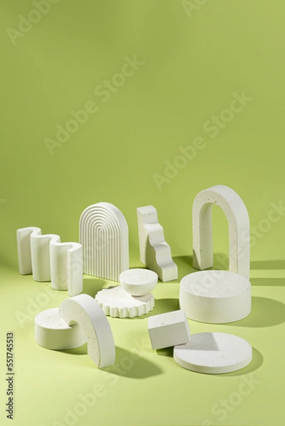 Fototapeta An empty stage with a composition of white podiums of different sizes and shapes on a green background and shadows