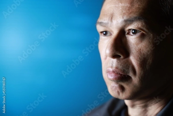 Fototapeta A craftsman poses in gray work clothes in front of blue shutter of a factory. Conceptual images of the essence of manufacturing, technical succession and the challenge of high-precision machining.