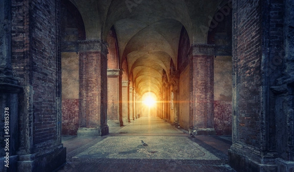 Fototapeta Rays of divine light illuminate old arches and columns of ancient buildings. Bologna, Italy. Conceptual image on historical, religious and travel theme.
