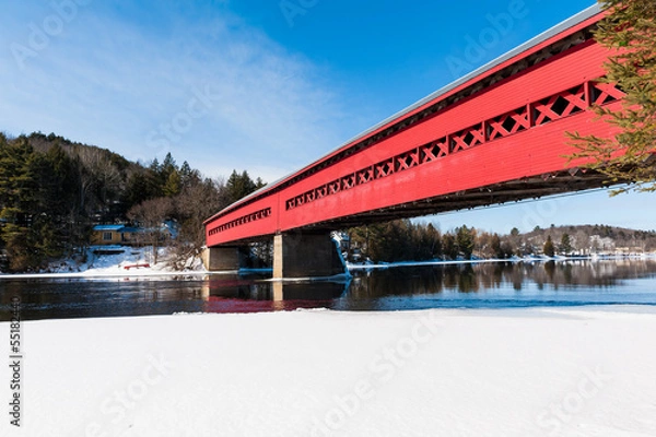 Fototapeta The covered red bridge above the river in winter