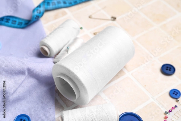 Fototapeta Thread spools on light tile, closeup