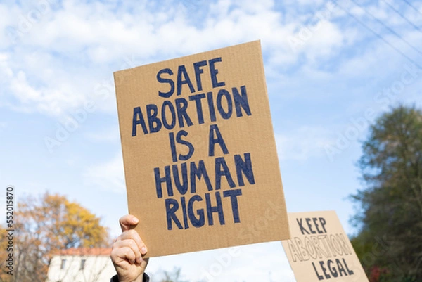 Fototapeta Protesters holding signs with slogans Safe abortion is a human right and Keep abortion legal. People with placards supporting abortion at protest rally demonstration.