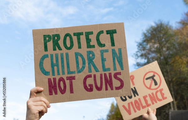 Fototapeta Protesters holding signs with slogans Protect Children Not Guns and Stop Gun Violence. People with placards at protest rally demonstration strike to ban weapons and end shooting.