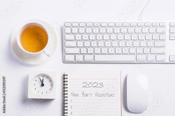 Obraz Conceptual,mouse and keyboard with clock and tea on white blackground work space.open diary with new year's resolutions 2023