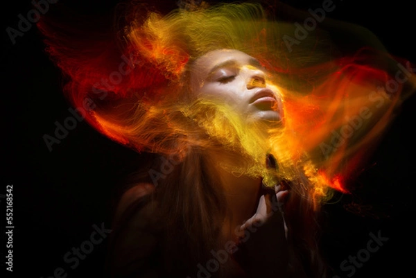 Fototapeta Abstract photography in the style of light painting. girl on a black background