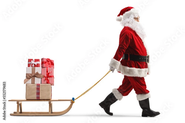 Fototapeta Full length profile shot of santa claus pulling a wooden sled with presents