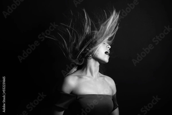 Fototapeta Fashion and make-up concept. Studio portrait of beautiful woman with evening make-up and flying hair. Image contains motion blur. Model with sensual facial expression. Black and white image