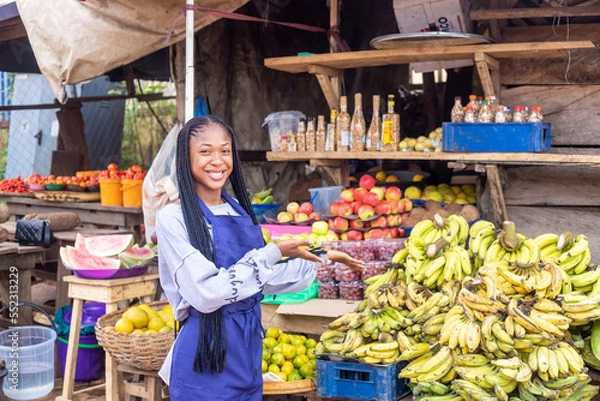 Obraz portrait of an african market woman smiling showing her goods
